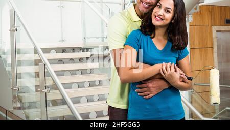 Composite image of caucasian couple hugging and smiling against stairs in background Stock Photo