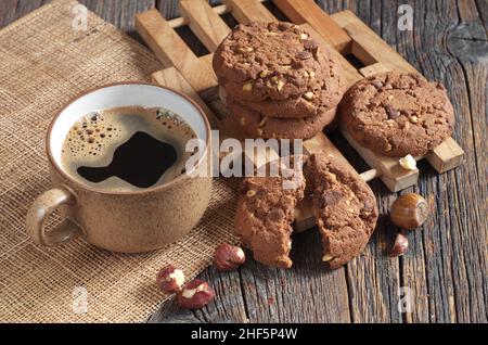 Cup of coffee and chocolate chip cookies with hazelnuts on old wooden table Stock Photo