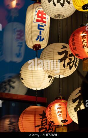 Many colorful traditional Illuminated paper lanterns hanging from ceiling in asian restaurant Stock Photo