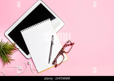 Digital tablet, notepad and a pen on a pink background with copy space Stock Photo