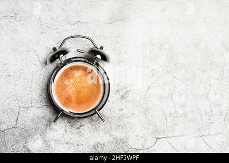 Bell alarm clock with a cup of coffe in clock face on a marble background with copy space Stock Photo