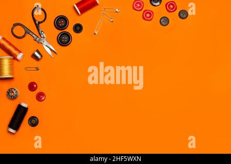 Scissors, sewing thread, colored buttons and sewing accessories on an orange background Stock Photo