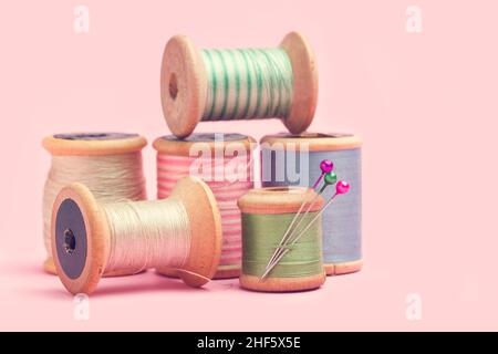 Colored thread spools on a pink background Stock Photo