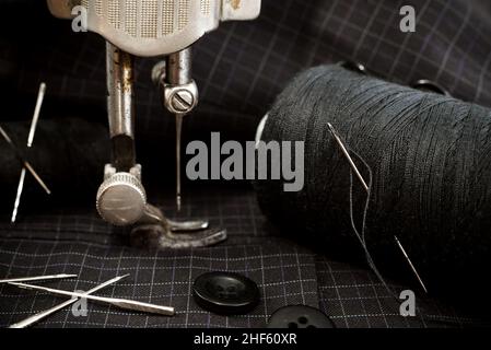 Old retro sewing machine, needle with thread, scissors and thimble. Tailor, seamstress and fashion designer tools for sewing clothes. Handmade Stock Photo