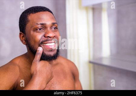 good-looking brazilian man smiling morning cheer up himself looking at mirror in bathroom Stock Photo