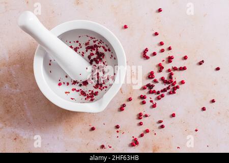 White pestle and mortar with pink peppercorn. Stock Photo