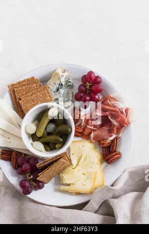 Winter cheese plate with a variety of Irish cheeses, grapes, prosciutto ham, pecan nuts and pickled cornichons and pearl onions. Stock Photo