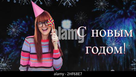 Portrait of smiling caucasian woman holding candy enjoying by russian orthodox new year on fireworks Stock Photo