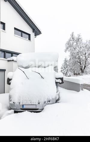 Snowed in camper with snow on the roof in front of a residential building Stock Photo