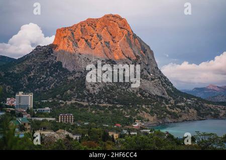 Mount Falcon lit by pink sunset in Novyi Svit during autumn season. Sudak,  the Republic of Crimea. Aerial view. Stock Photo