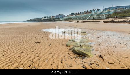 The linear patterns on the sand caused by the outgoing tide, with the Promenade in the background in Whitley Bay, England Stock Photo