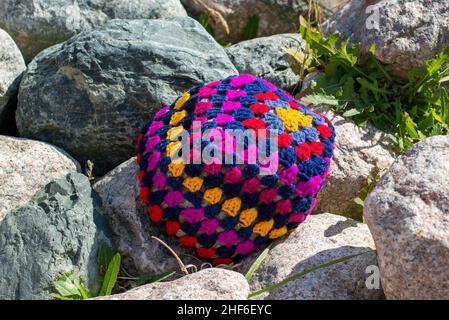A colorful craft crocheted pillow, multicolored; red, purple, blue, and yellow color cotton wool. The textile pattern in the handmade pillow is a flow Stock Photo