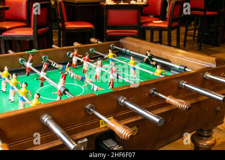 Foosball table with miniature male players. Enjoyment leisure entertainment activity for friends to play table football soccer in pubs and bars. Frien Stock Photo