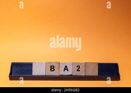 BA2. New variant of the SARS-CoV-2 coronavirus. Subvariant of Omicron. Text written on square pieces of wood. Background with orange space. Horizontal Stock Photo