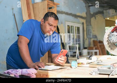 latin man checking orders on cell phone Stock Photo
