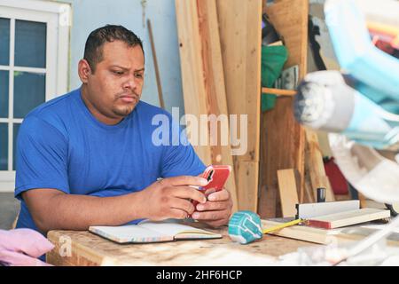 latin man checking orders on cell phone Stock Photo