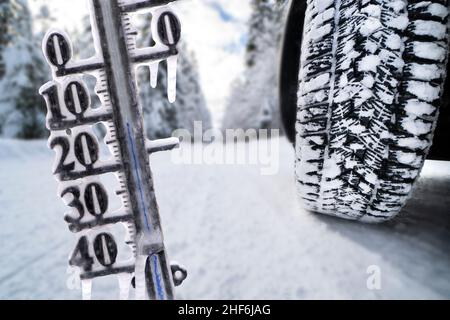 Thermometer shows cold temperature and icicles in winter with slippery road Stock Photo