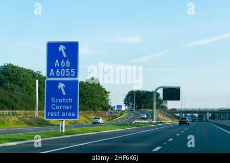 Leeds, UK - 23rd August 2019: Cars drive down the A1 British motorway with blue highway signs directing drivers to Scotch Corner rest area service Stock Photo