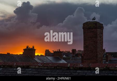 A view across roofs at sunset as a menacing storm cloud looms overhead Stock Photo