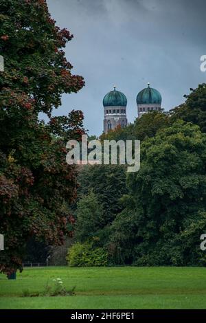 View at the mostly hidden Frauenkirche of Munich in the autumn season with a green foreground,  concept for the wonderful green bavarian capital Stock Photo