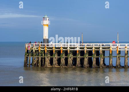 Sea anglers with large fishing rods casting their lines from wooden pier / jetty at the Nieuwpoort / Nieuport harbour entrance along the Belgian North Stock Photo