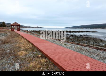 A wooden pier with a large square hut at the wharf. The platform marina has a wooden rail around the wharf and a metal roof. The gazebo stage is over Stock Photo