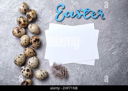 Top view of small quail eggs for Easter day and mock-up of blank white card on grey concrete background Stock Photo
