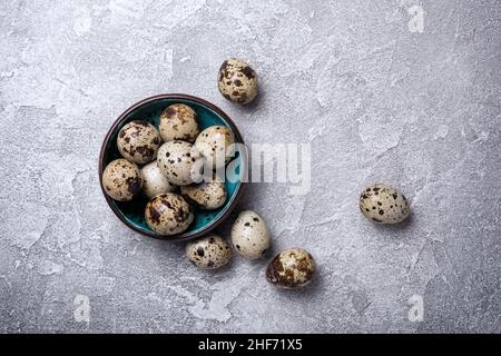 Top view of small quail eggs in bowl on grey concrete background Stock Photo