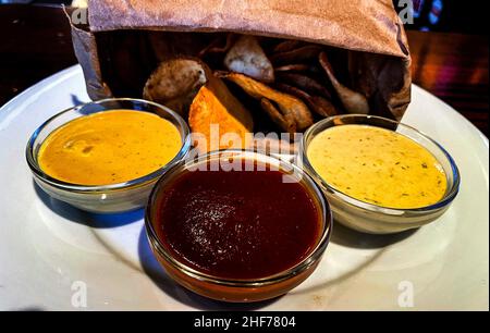 Crisps in a paper bag and three sauces, yummy Stock Photo