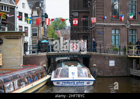 Amsterdam, Holland, The Netherlands - 6th May 2019: Numerous different nationality flags flying in the wind on the canal in Amsterdam on a summers day
