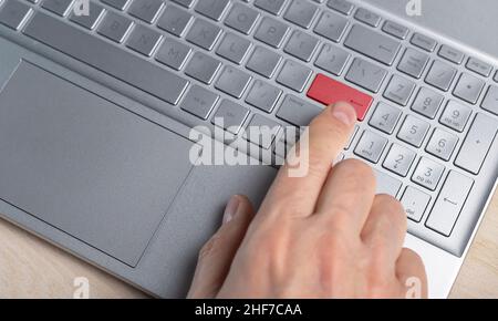 Finger pressing red warning button on laptop computer. Stock Photo