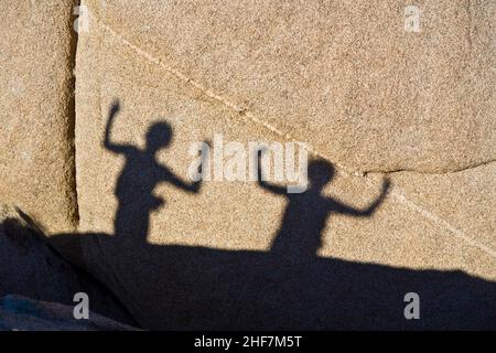 children playing with shadows on a rock in Jushua Tree National park Stock Photo