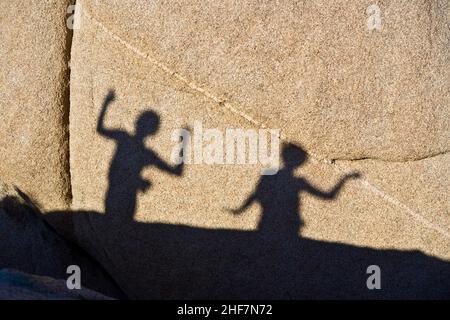 children playing with shadows on a rock in Jushua Tree National park Stock Photo