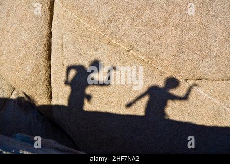 children playing with shadows on a rock in Jushua Tree National park Stock Photo