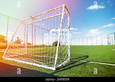 Amateur soccer field with goal, back view, lens flare and blue sky. Stock Photo