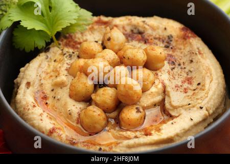 Closeup photo of tasty chickpeas hummus in black plate with smoked paprika Stock Photo
