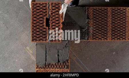 Mason making wall with mortar and bricks. Close up of industrial worker hands building a wall of new house. Stock Photo