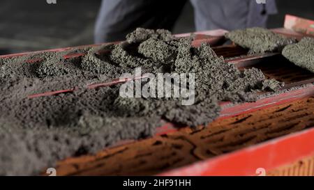 Bricklayer putting down raw cement and making an even layer to put another brick on it. Close up of making a brick wall process. Stock Photo