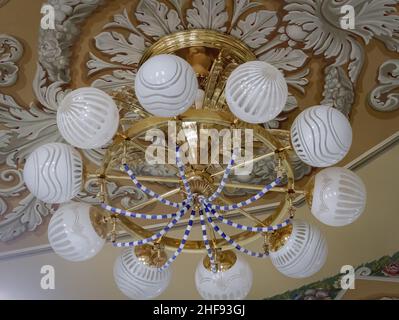 Ceiling lamp with round white shades. Antique brass finish ceiling lamp with opal shades and gold lining. Gold metal pendant lamp. Hanging lamp. Stock Photo