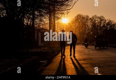 Srinagar, India. 11th Jan, 2022. Silhouette of people walking along the road during sunset. Credit: SOPA Images Limited/Alamy Live News Stock Photo