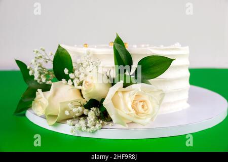 Wedding cake with white roses on green background. Close up. Stock Photo