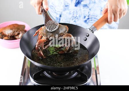 Home Cooking  Process Making Singaporean Chilli Mud Crab, Fried Crab in Hot Oil on Black Wok Stock Photo