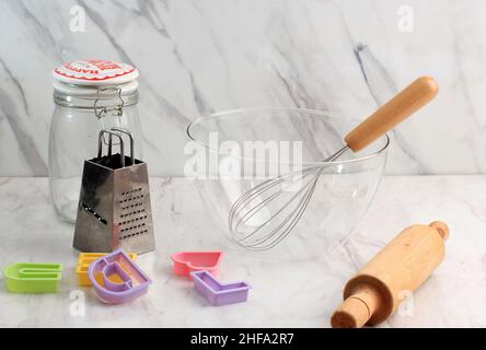 Empty Baking Bowl, Grater, Jar, Cookie Cutter, and Rolling Pin in White Marble Kitchen, Concept Baking Preparation Stock Photo
