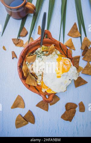 Clay pot of chilaquiles with fried egg on top and above white surface Stock Photo