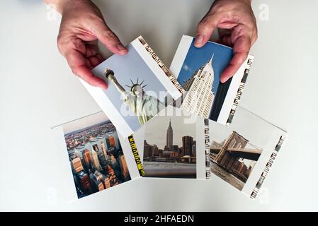 Woman hands holding photo prints of New York City isolated on white background. Travelling in USA concept. Stock Photo