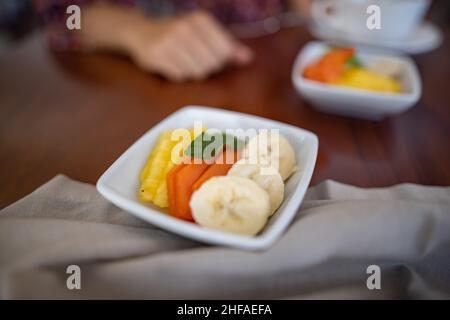 Square plates with fresh fruit slices on brown table Stock Photo