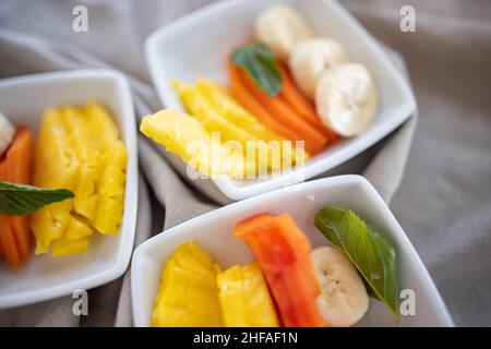 Square plates with fresh fruit slices on wrinkled gray napkin Stock Photo