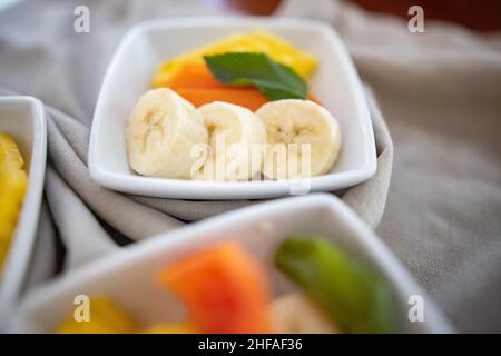 Square plates with fresh fruit slices on wrinkled gray napkin Stock Photo