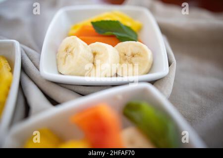 Square plates with fresh fruit slices on wrinkled gray napkin Stock Photo
