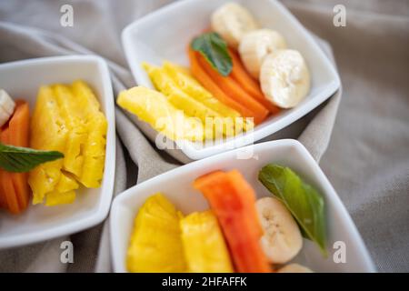 Square plates with fresh fruit slices on wrinkled gray napkin Stock Photo